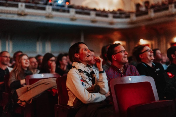 Spectateurs souriants dans une salle, captivés par un événement cinématographique divertissant.