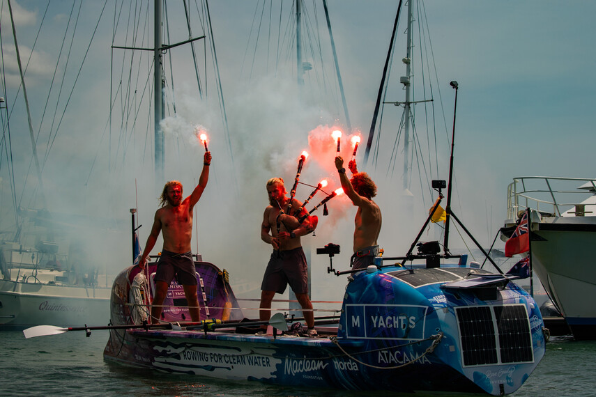 The Maclean brothers are standing on their rowboat, celebrating with torches in the harbor